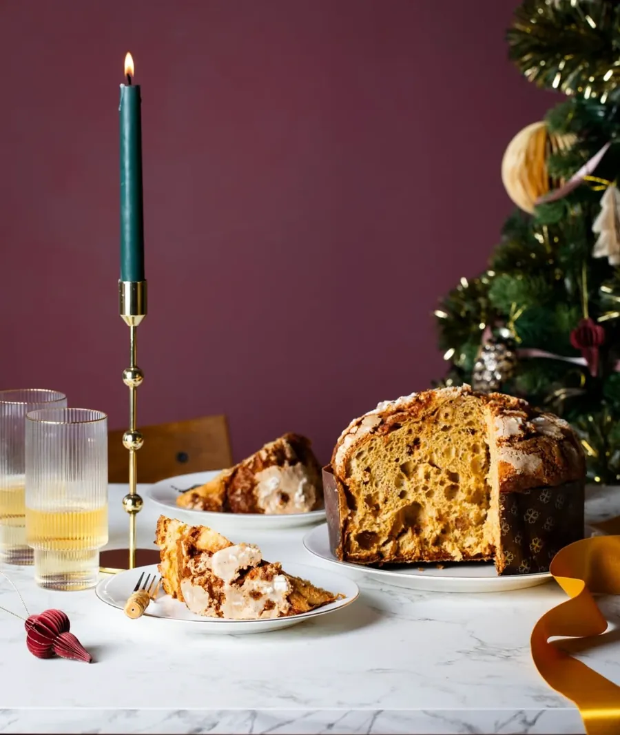 Panettone classico Cerea tagliato, con uvetta e arancia candita, su una tavola natalizia con candela